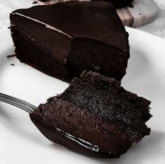 a piece of chocolate cake on a white plate with a fork in front of it