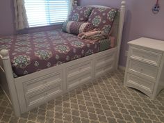 a bedroom with purple walls and white drawers