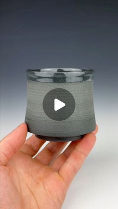 a hand holding a small cup with a video playing button on the inside of it