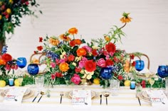 the table is set with colorful flowers and place settings