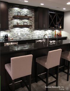 a modern kitchen with bar stools and dark wood cabinets