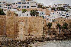 some buildings are next to the water with people sitting on rocks in front of them