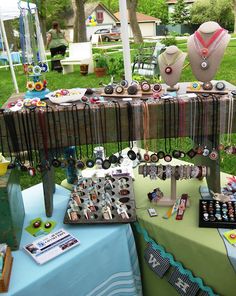 there are many items on the table at this outdoor market stall, including necklaces and bracelets