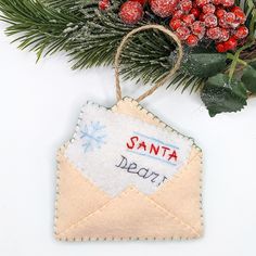 an ornament hanging from a christmas tree branch with berries and evergreen branches in the background