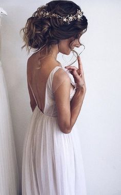 the back of a woman's dress, with her hand on her hip and wearing a flower crown