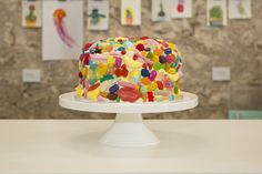 a colorful cake sitting on top of a white plate covered in gummy bears and sprinkles