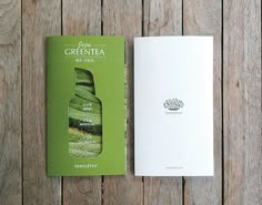 a green tea book sitting on top of a wooden table next to a white box