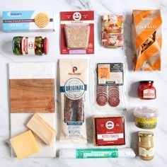 an assortment of food items laid out on a marble counter top, including bread, cheese, and other ingredients