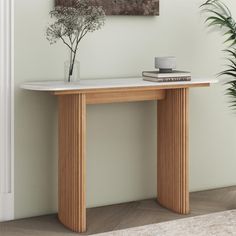 a white marble top console table with wood trimmings and a plant in the corner