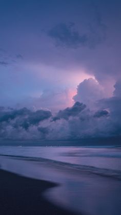 the sky is purple and blue over the water at dusk on an ocean beach with waves coming in to shore