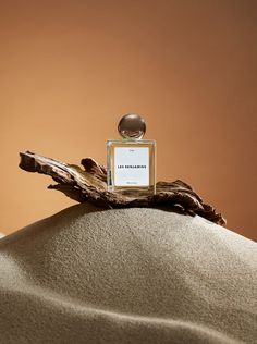 a bottle of perfume sitting on top of a sand dune