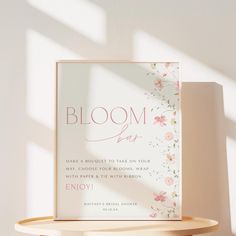 a sign that says bloom is on top of a wooden shelf next to a white wall