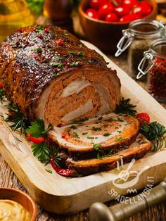 a meatloaf on a cutting board with herbs and tomatoes