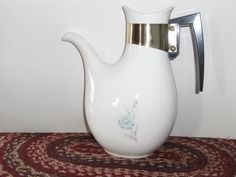 a white vase sitting on top of a red rug next to a wall mounted hook