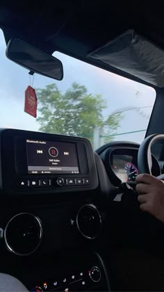 a man driving a car on a road with trees in the background