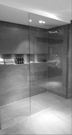 a bathroom with a glass shower door and tile flooring in black and white photo