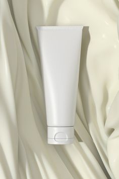 a tube of cream sitting on top of a white cloth covered with flowing fabric,