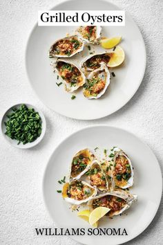 two white plates topped with oysters and garnish