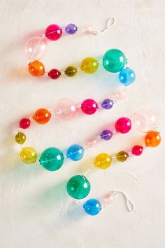 three different colored beads hanging from strings on a white surface with one bead in the middle