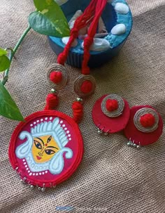 two red and white necklaces sitting on top of a table next to a potted plant