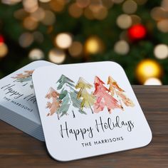 two business cards sitting on top of a wooden table next to a christmas tree with lights in the background