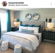 a bedroom decorated in teal and white with two round mirrors above the headboard