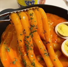 carrots are being cooked in a pan with yogurt and herbs on top