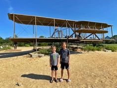 two young boys standing in front of an airplane