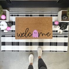 someone standing in front of a welcome mat with a pink ghost on it and the words welcome