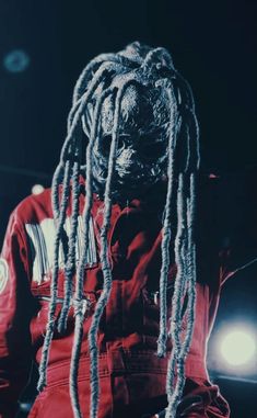 a man with dreadlocks standing in the dark