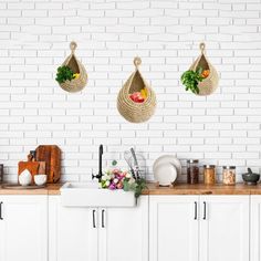 the kitchen is clean and ready for us to use it's white walls are lined with hanging baskets