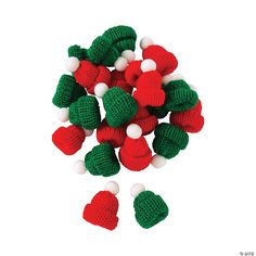 a pile of knitted christmas decorations on a white background with red, green and white pom - poms