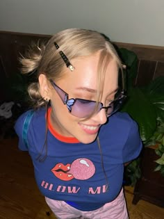 a woman wearing sunglasses and smiling while standing on a wooden floor in front of a potted plant