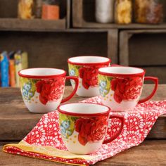 four red and white coffee cups sitting on top of a wooden table next to a napkin