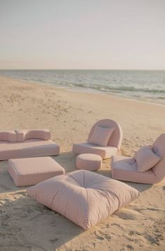 pink cushions and pillows are arranged on the beach