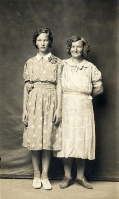 an old photo of two women standing next to each other