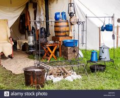 an old fashioned tent with many pots and pans on the ground in front of it