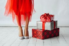 a woman's feet in high heels standing next to three wrapped presents on top of each other