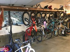 many bikes are parked in a bike shop with bicycles hanging on the wall behind them