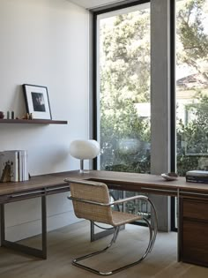 an office with a desk and chair in front of a large window that looks out onto the trees outside