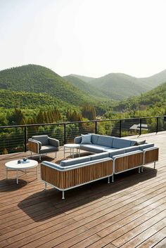 a wooden deck with two couches and a coffee table on it, overlooking the mountains