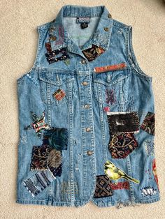 Denim Vest, Embellished Vest, Distressed, Applique, Upcycled Vest, Bird, Flower, Jeans Vest, Embroidered Vest, Repurposed, Collage, Hippie This is a one-of-a-kind, embellished upcycled denim vest. I distressed it by hand, so it has some tatters and holes. The vest has buttons up the front, and two button-closure pockets on the chest.  The tag says, "Denim Old School". I have decorated it with hand embroidery, appliques, including a star, a bird, a flower, patches of various bits of fabrics, and I added vintage metal buttons to the collar.      I foraged in my exisitng stash of vintage fabric and supplies for the appliques and other bits of embellishment. Everything has been securely handsewn with the exception of around the appliques.  The vest is soft, weathered 100% Cotton. The size is m Upcycled Vest, Distressed Clothes, Distressed Outfit, Jeans Vest, Flower Jeans, Embroidered Vest, Jean Vest, Upcycled Denim, Vest Outfits