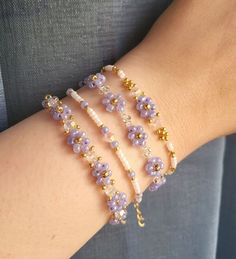 three bracelets with flowers and pearls on the arm, one in gold plated metal