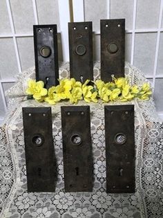 four pieces of metal are sitting on a lace tablecloth with yellow flowers in front of them