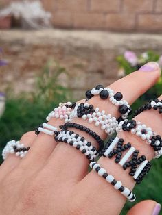 a woman's hand holding several bracelets made from beads and black and white beads