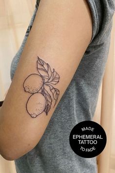 a woman with a tattoo on her arm that has lemons and leaves on it