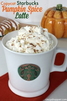 starbucks pumpkin spice latte with whipped cream in a white cup on a red place mat