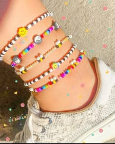 a woman's foot with several bracelets on it, including smiley face beads