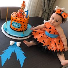 a baby sitting on top of a table next to a cake