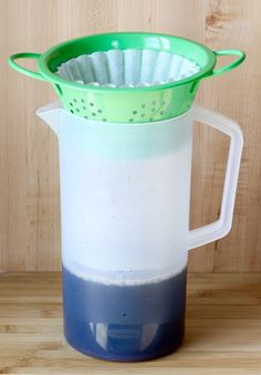 a pitcher filled with liquid sitting on top of a wooden table